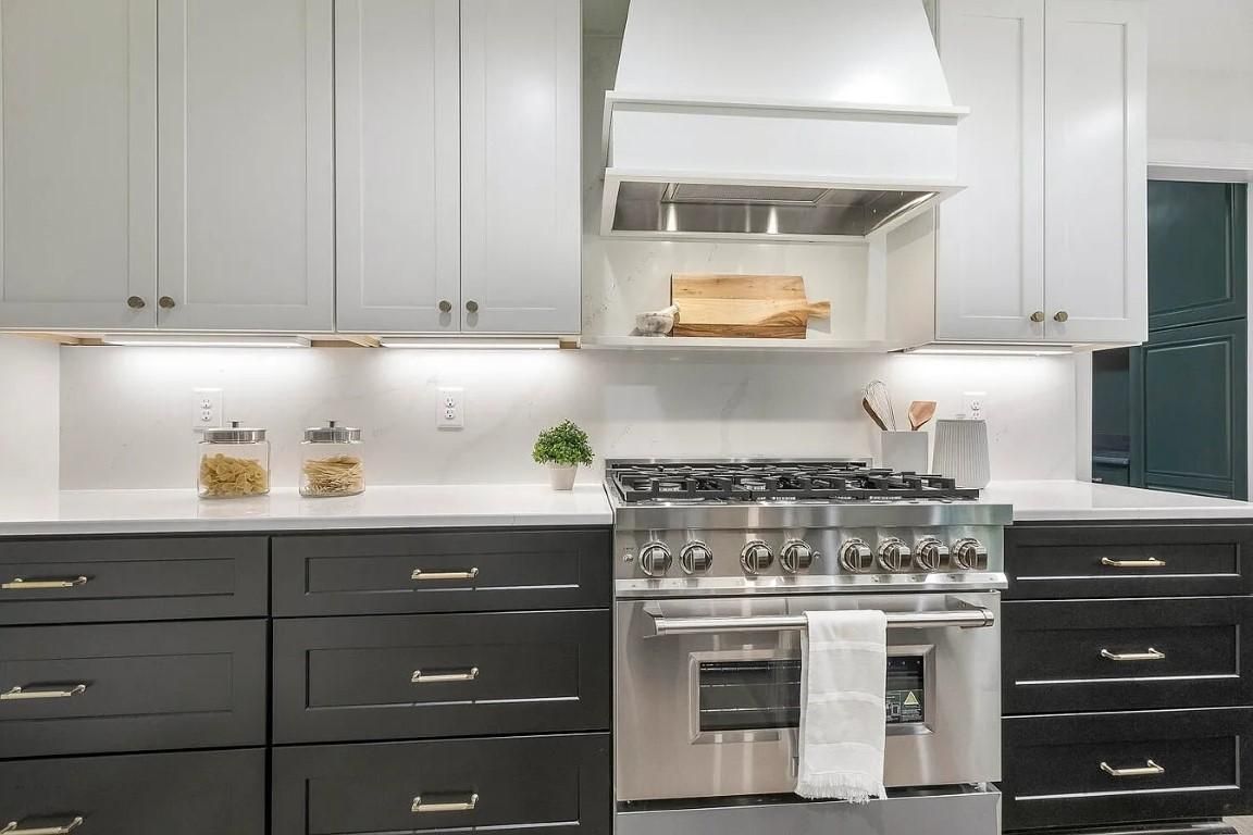 Modern kitchen with white and black cabinets, stainless steel stove, and white countertops.