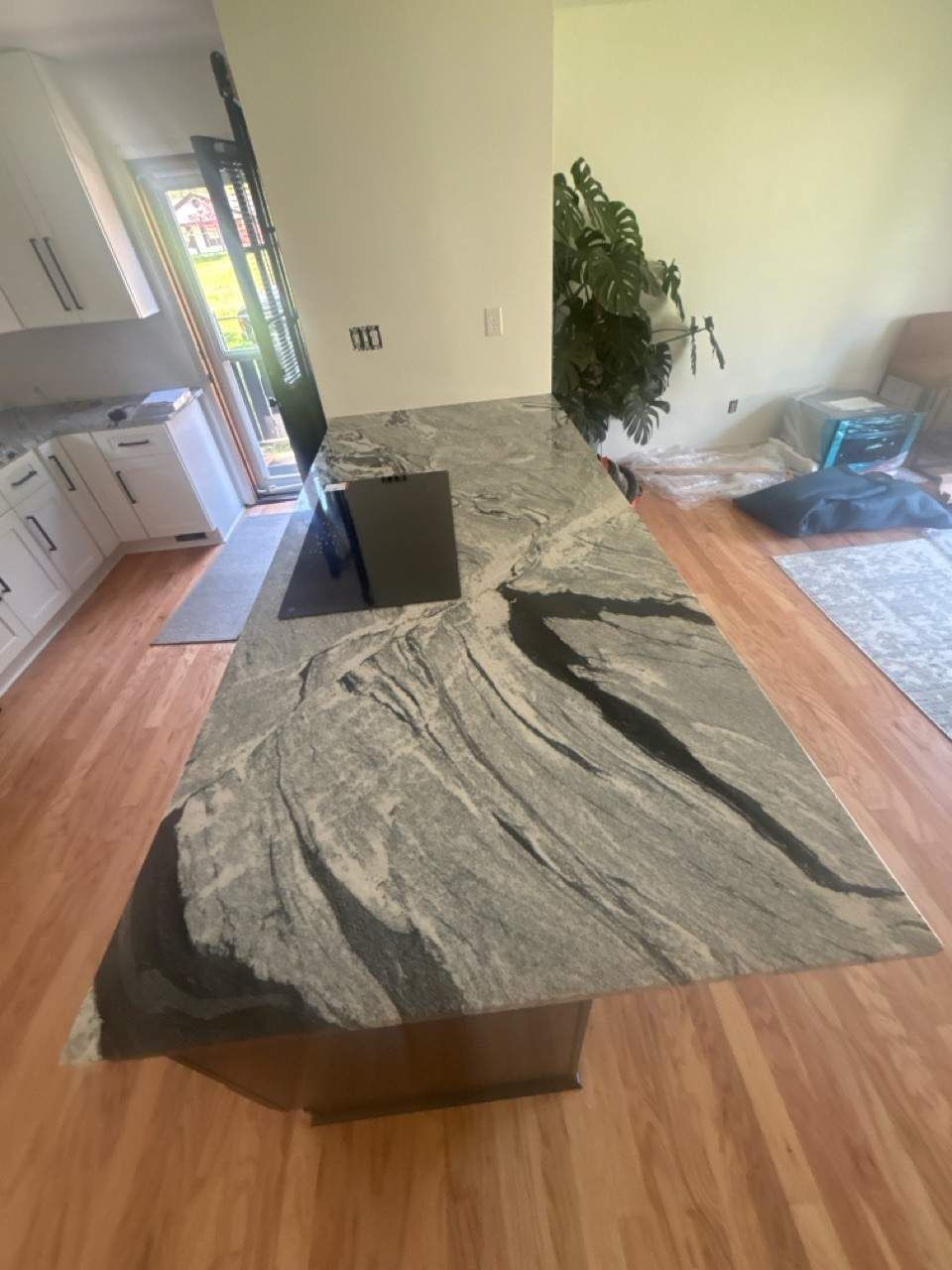 Kitchen island with gray and black granite countertop, brown cabinets, and hardwood floors.
