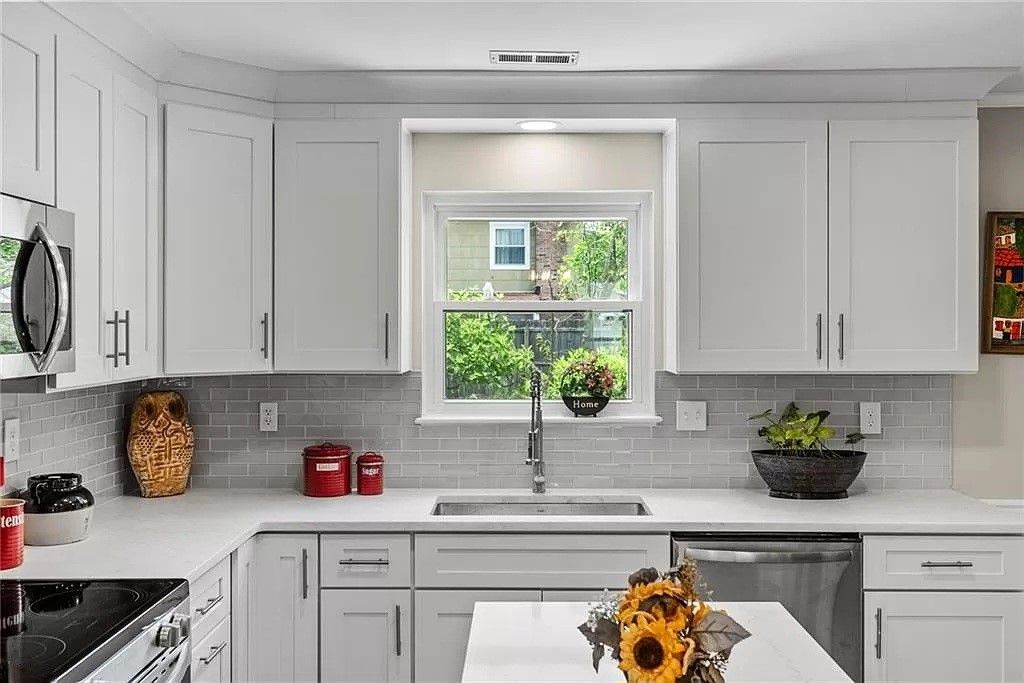 White kitchen with light countertops, cabinetry, and a window over the sink.