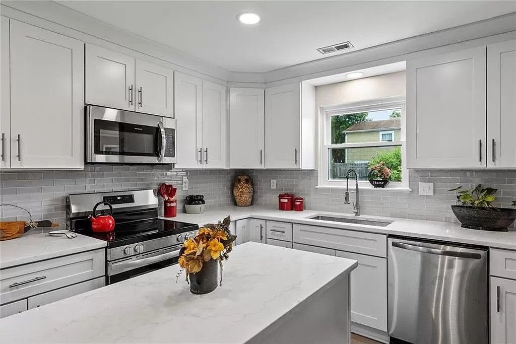 White kitchen with stainless steel appliances, white cabinets, and a kitchen island.