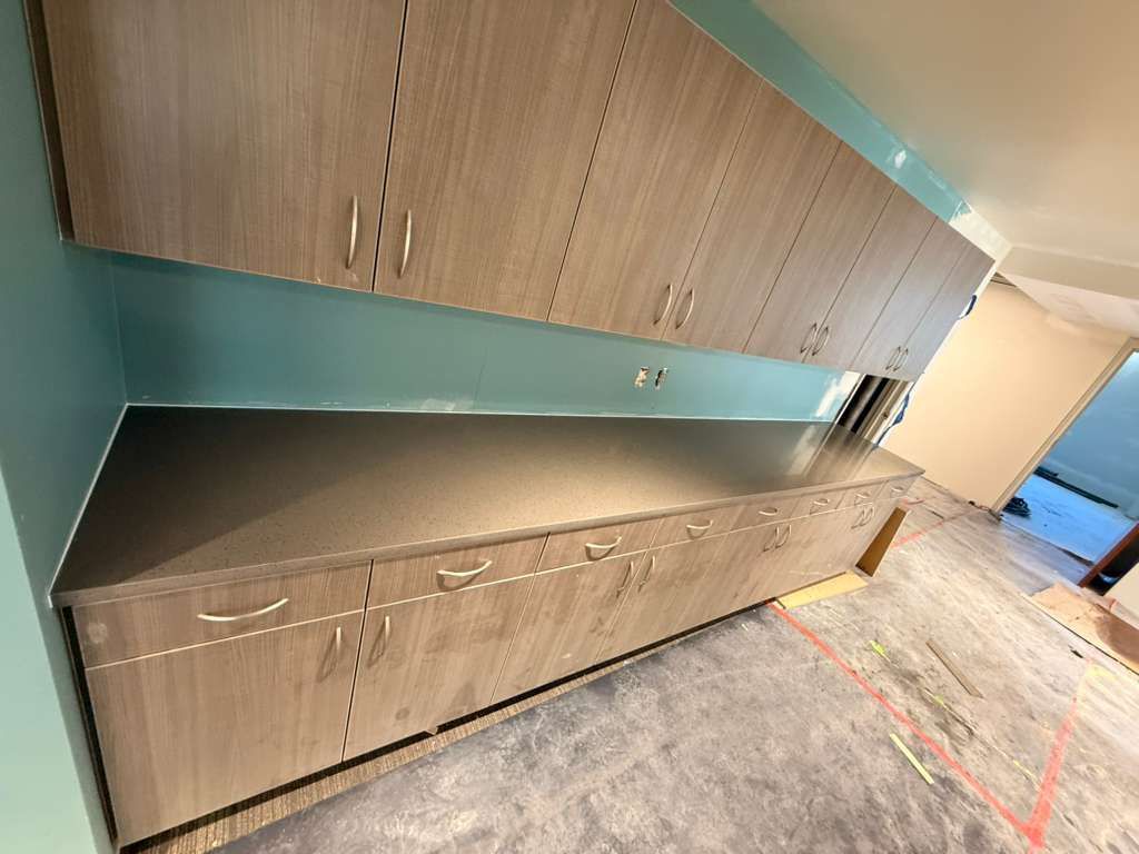 Gray cabinets and countertop on light blue wall. Cabinets in a room under construction.