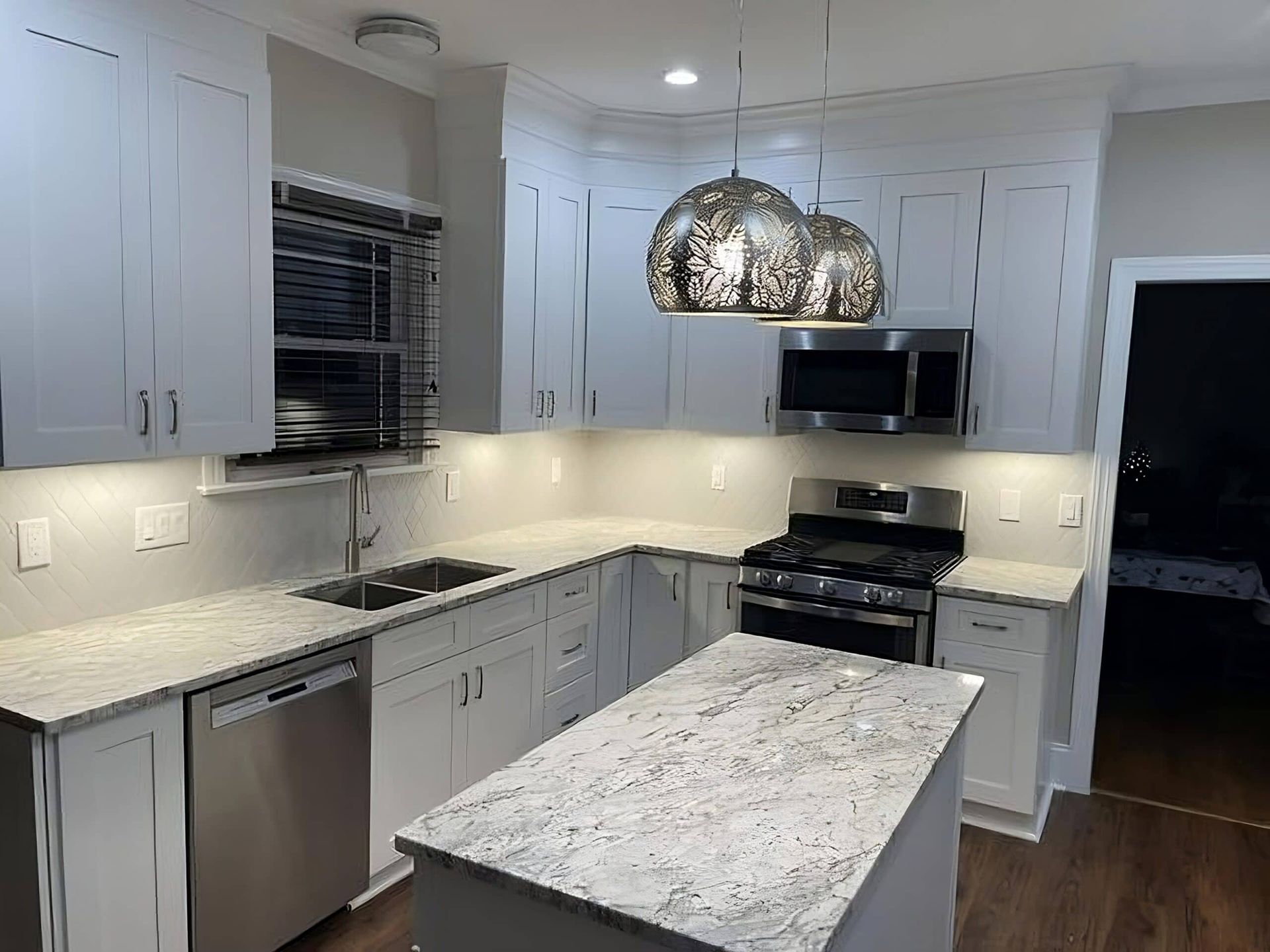 White kitchen with granite countertops, stainless steel appliances, and island.