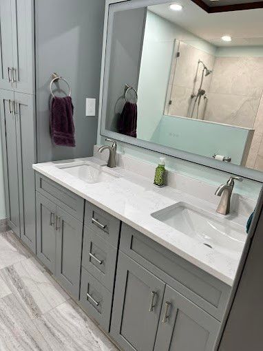 Gray bathroom with double vanity, large mirror, and shower visible.