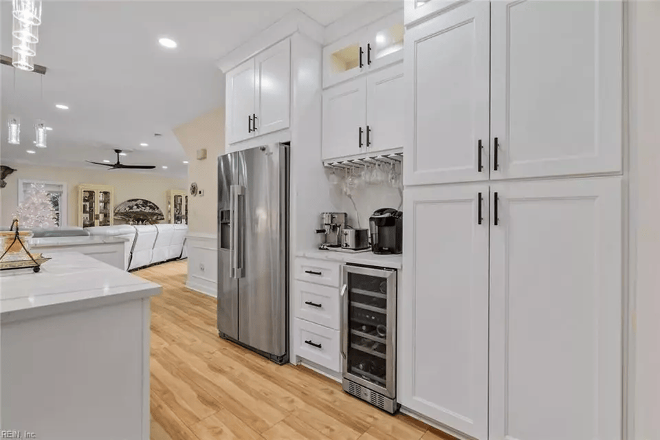 White kitchen with stainless steel appliances and cabinets; wine cooler; open to living area.
