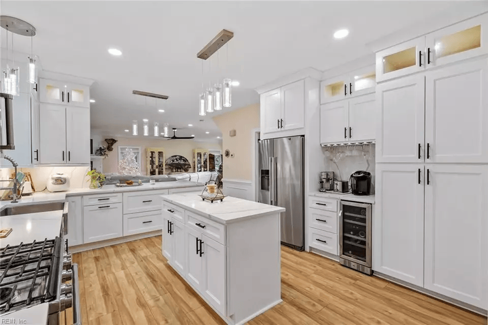 Bright white kitchen with stainless steel appliances, white cabinets, and a wooden floor.