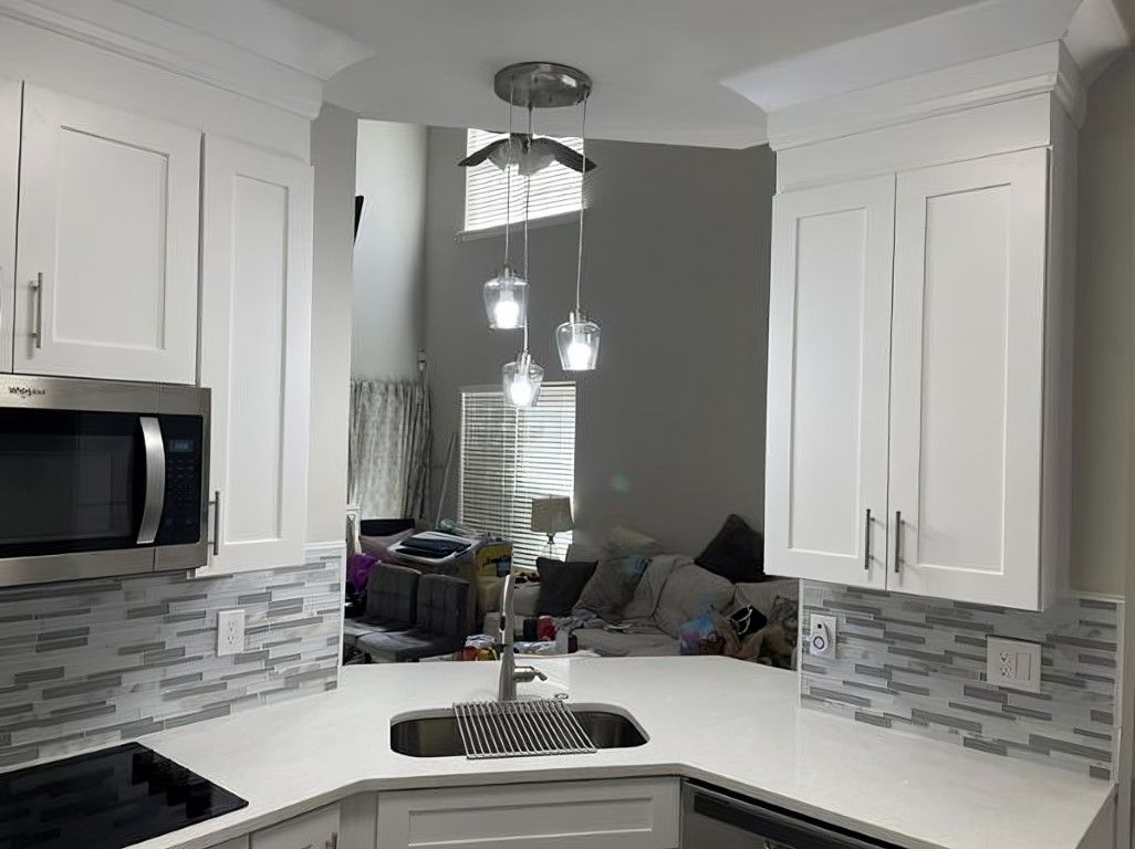 White kitchen with countertops, cabinets, sink, and pendant lights.