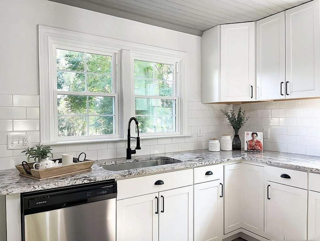 White kitchen with granite countertops, stainless steel appliances, and black hardware.
