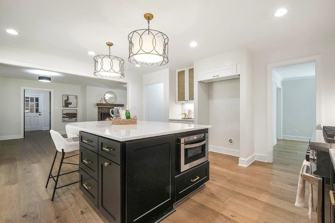 Kitchen with black island, white countertops, gold accents, and hardwood floors.