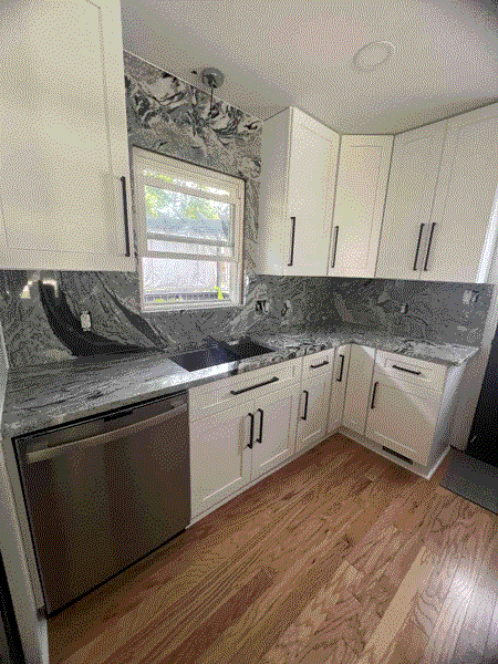 White kitchen cabinets with gray countertops and stainless steel appliances.