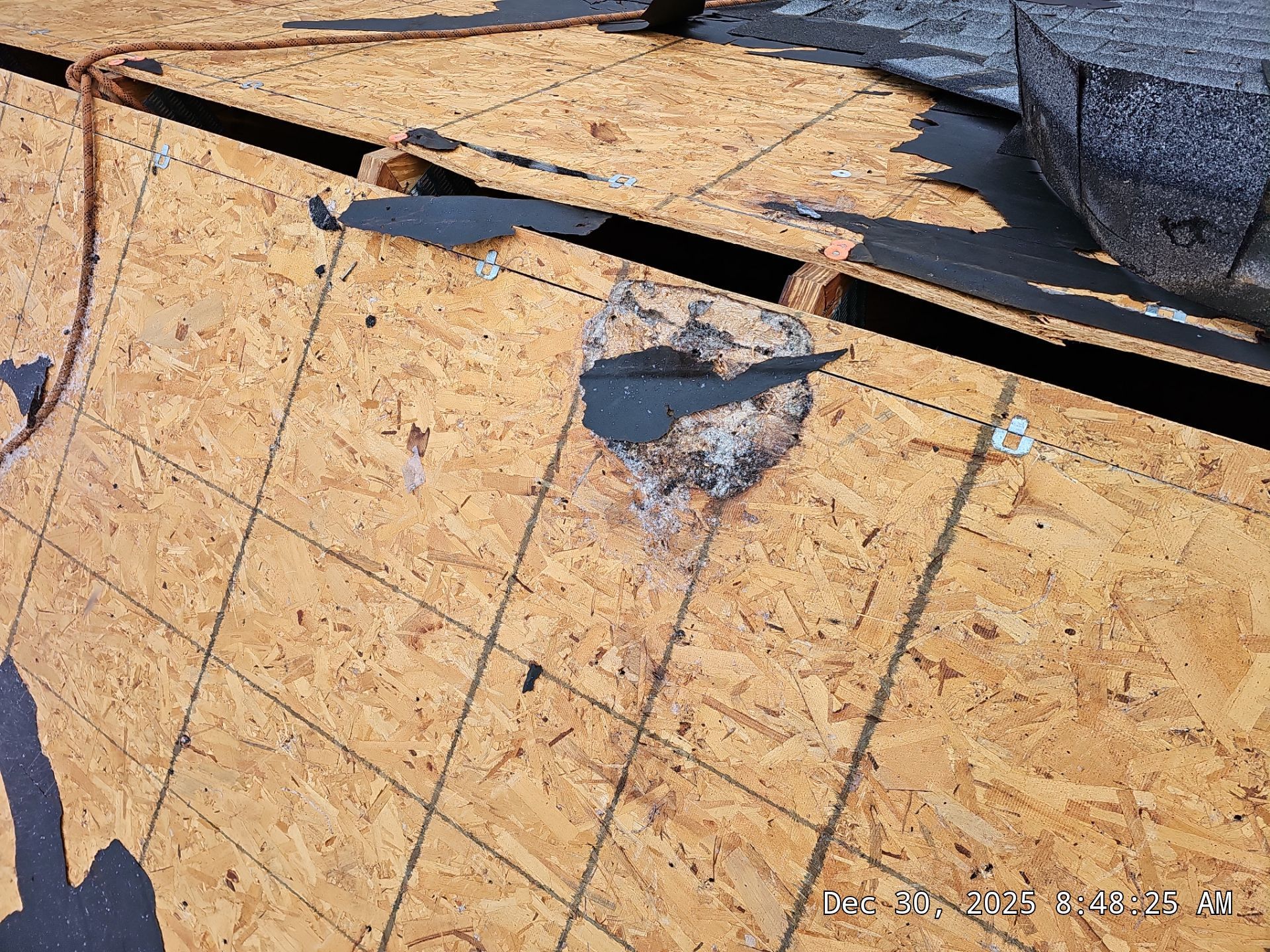 OSB roof decking with a patch of repair and a damaged area.