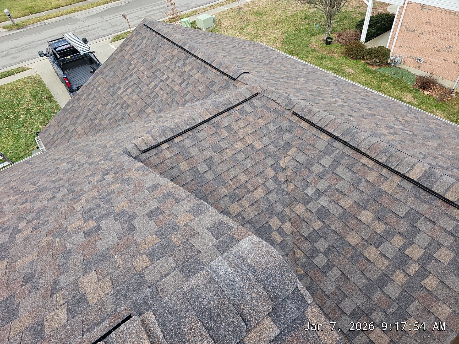 Overhead view of a brown shingle roof on a residential building with a truck parked in the driveway.