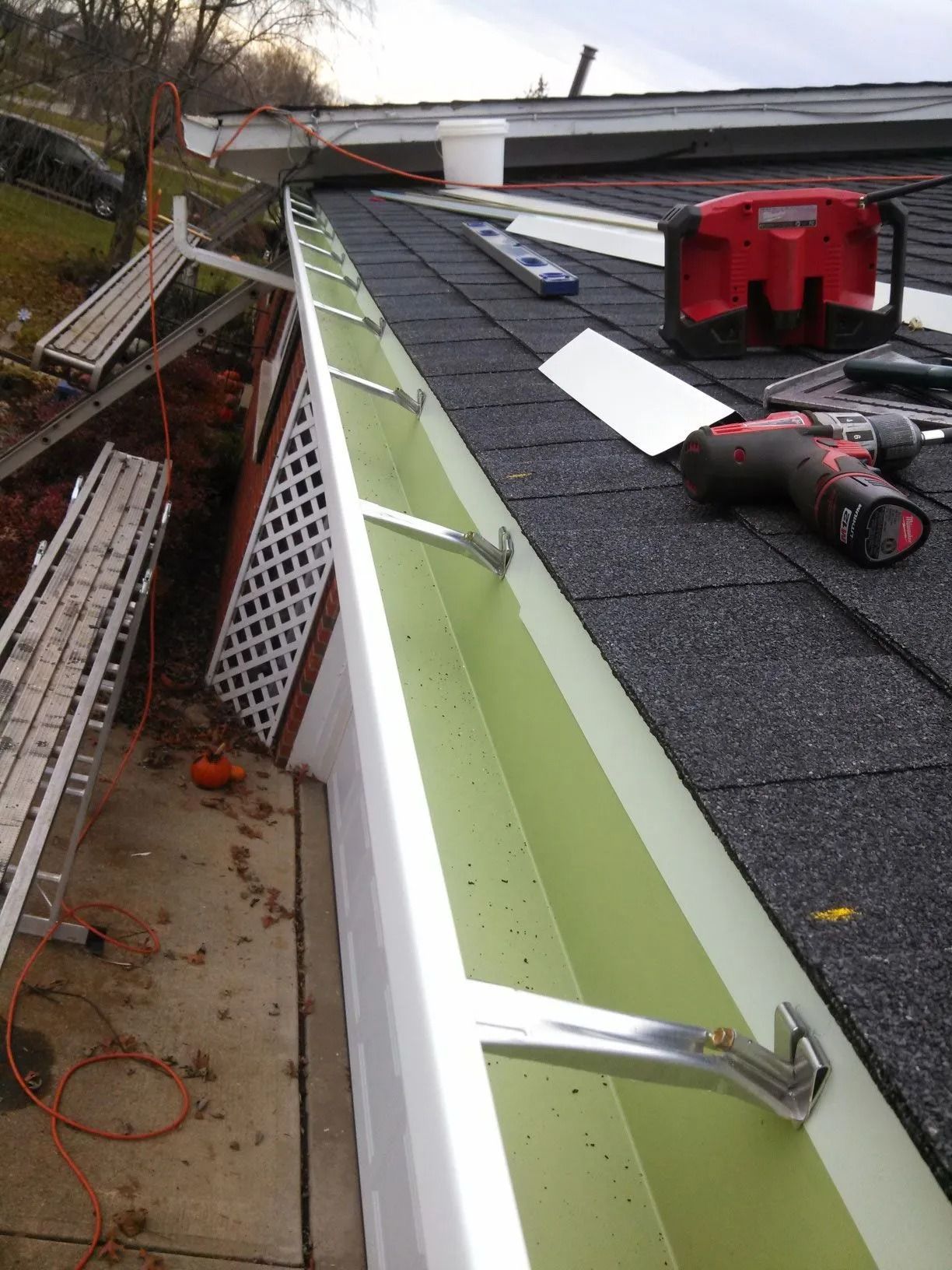 New gutters being installed on a house roof. Tools and materials are nearby.
