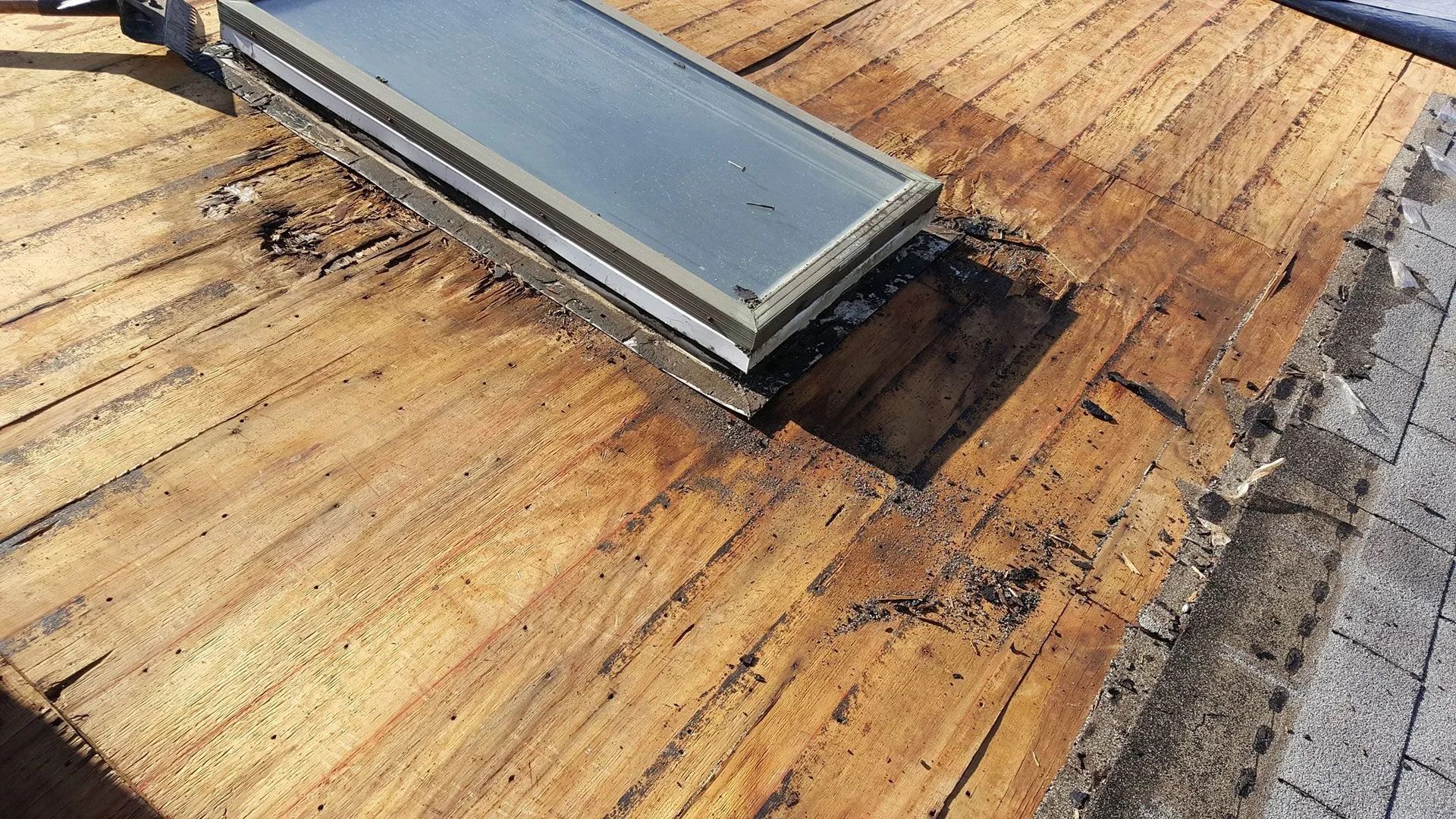 Skylight installed on weathered wooden planks, casting a dark shadow.