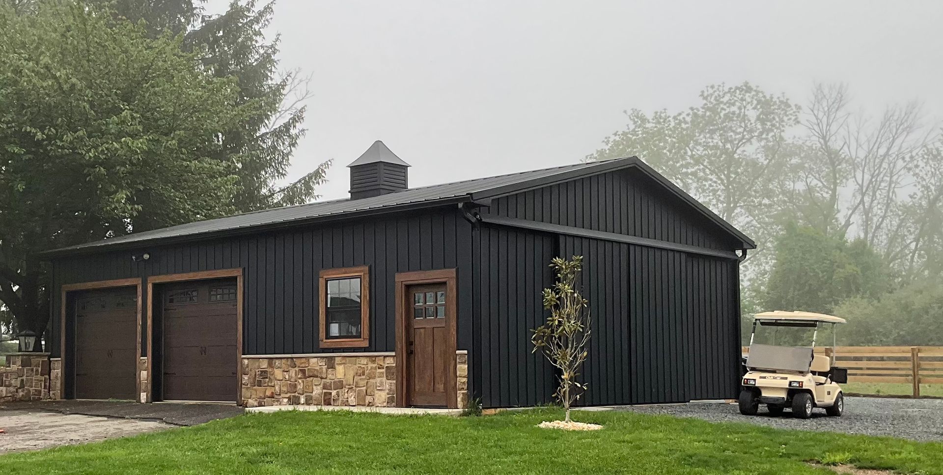 A black garage with a golf cart parked in front of it.