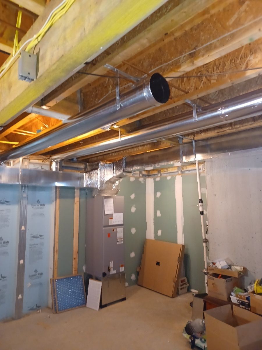 Basement with exposed ductwork, air handler, and unfinished walls.