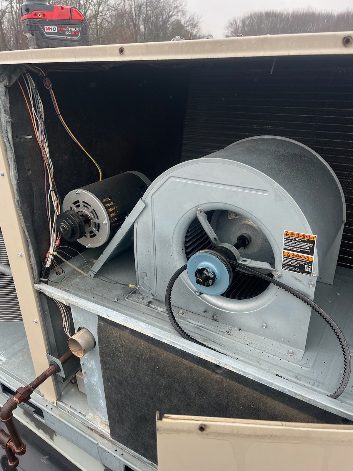 Open view of an HVAC unit's internal components, including a fan, motor, and electrical wiring.