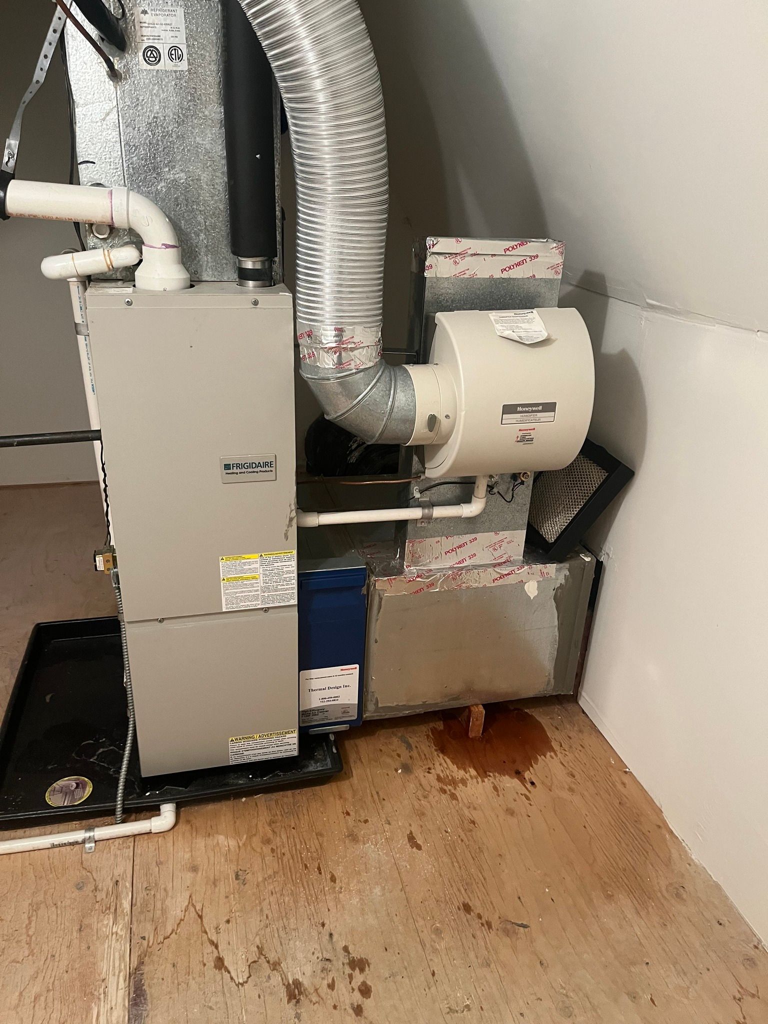 HVAC unit with a humidifier, located in an unfinished room with water on the floor.