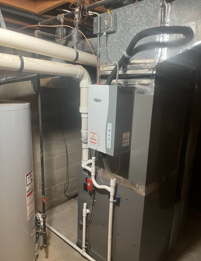 A basement with a hot water heater, furnace, and pipes. Gray and white with red accents.