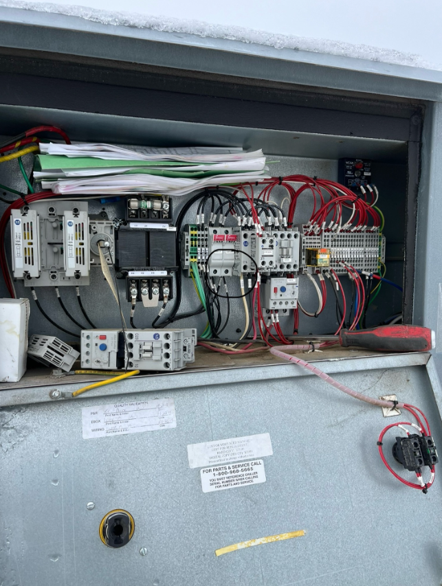 Electrical panel with wires, circuit breakers, and documentation.