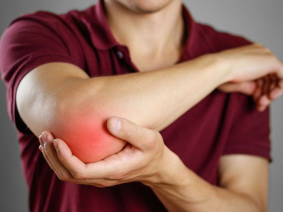 A man is holding his elbow in pain.