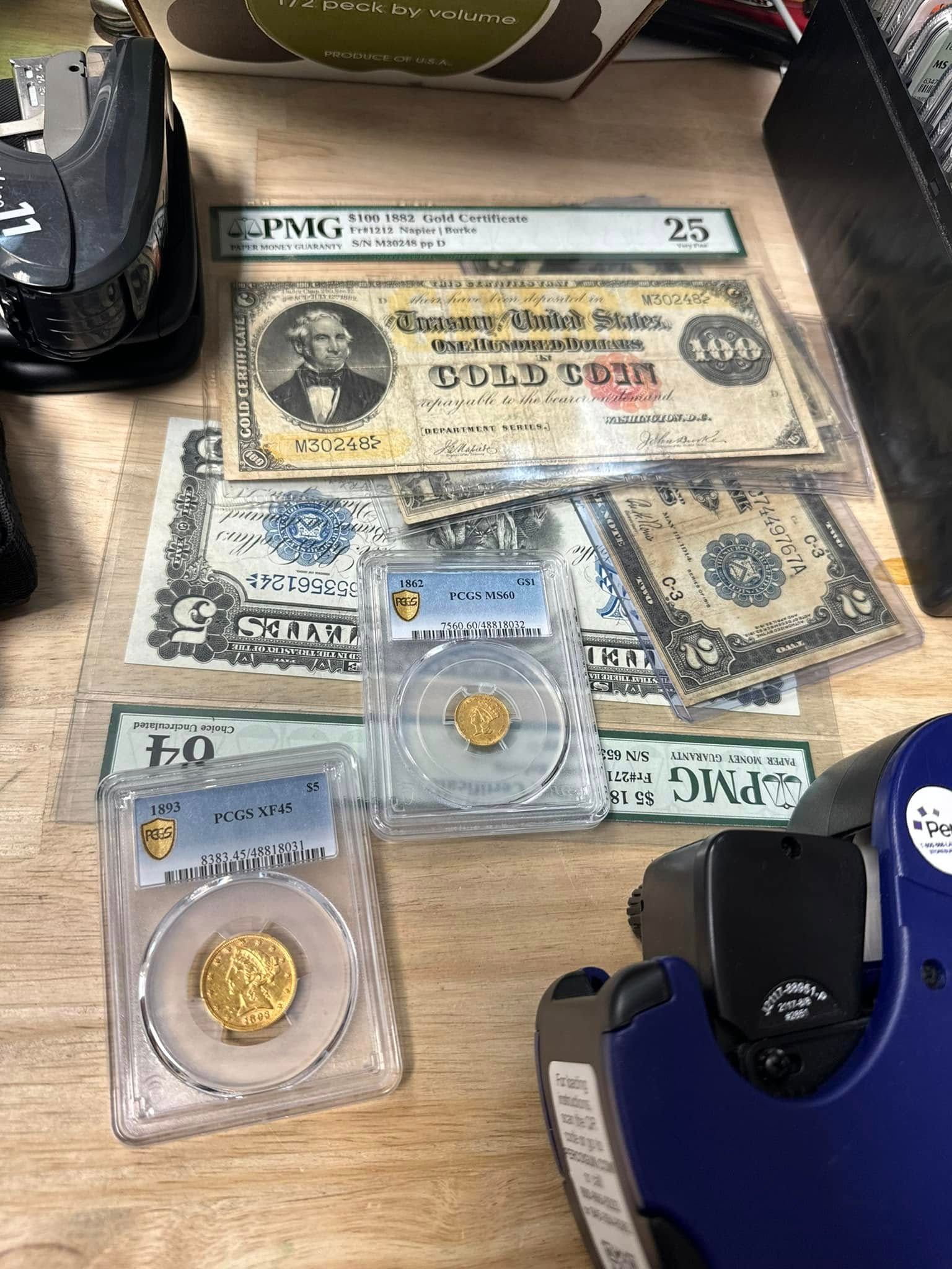 Assorted old banknotes and coins on a table, including a British 25 shilling note and coin cases.