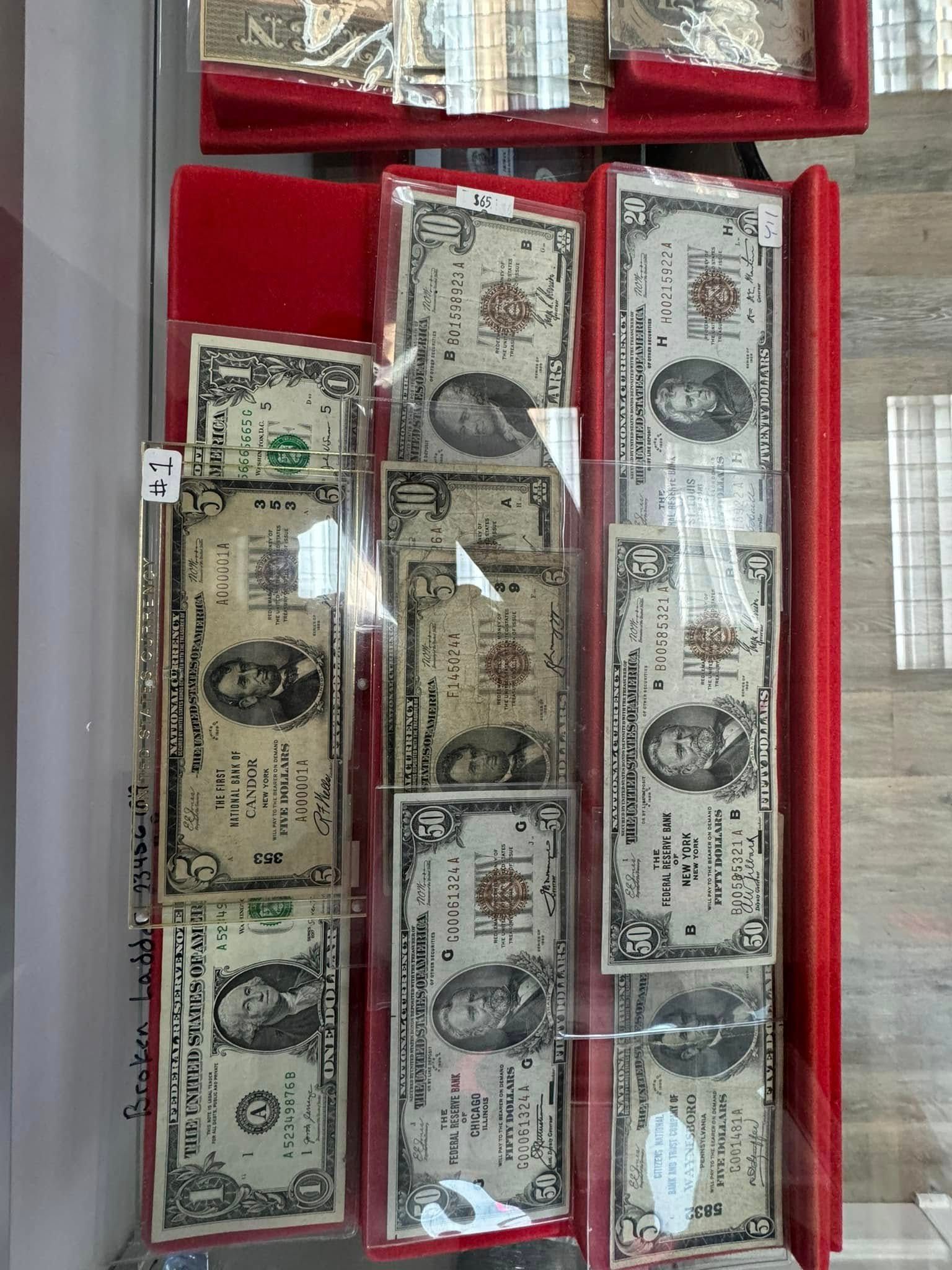 Open red display case with rows of old banknotes in various colors and denominations.