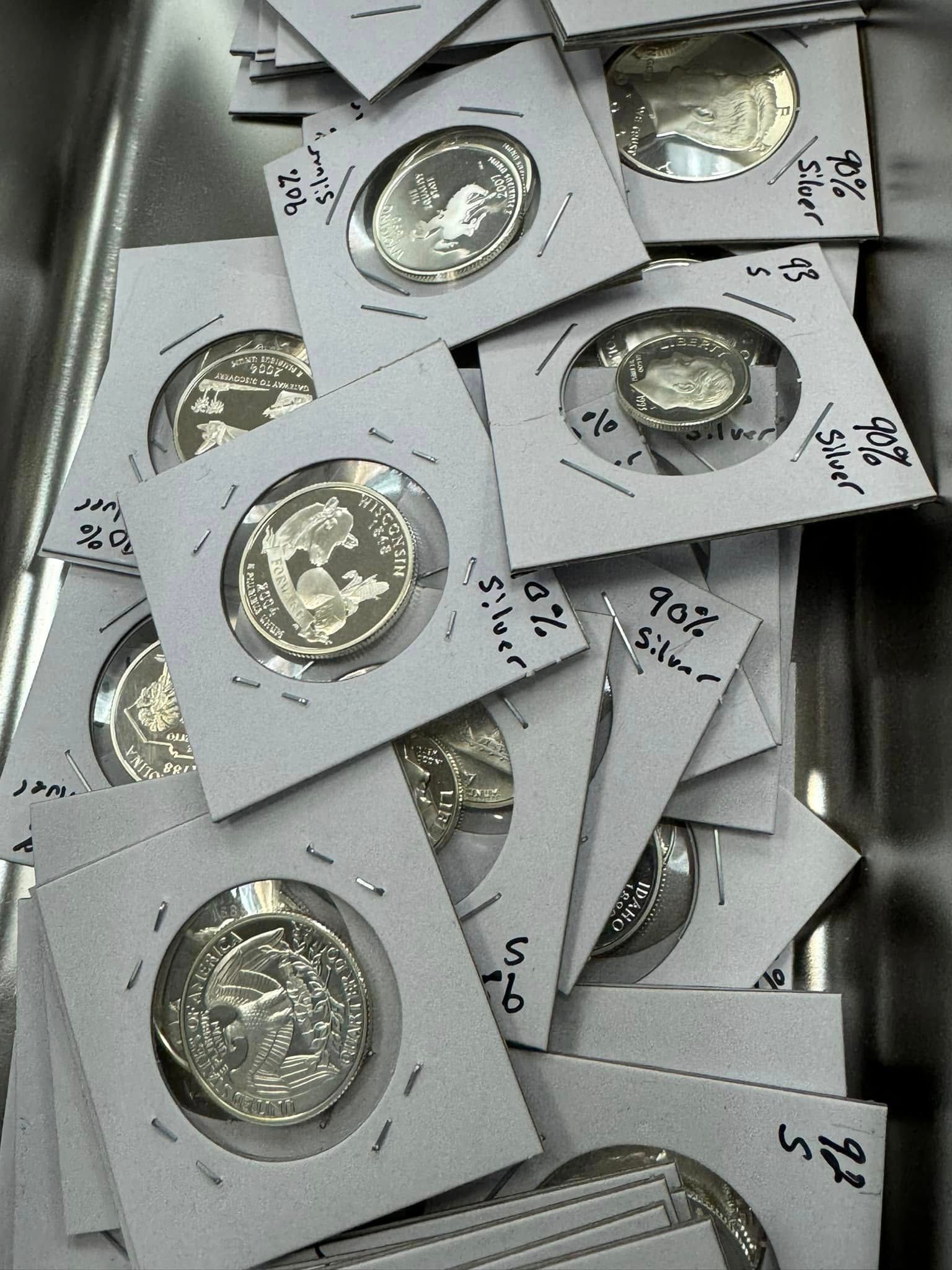 Stacked silver coins in cardboard coin holders in a tray