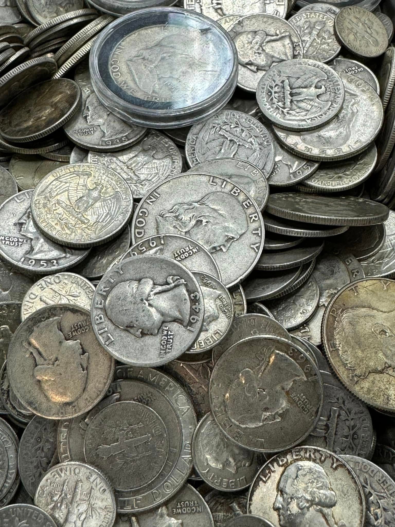 Pile of worn silver coins stacked and scattered closely together