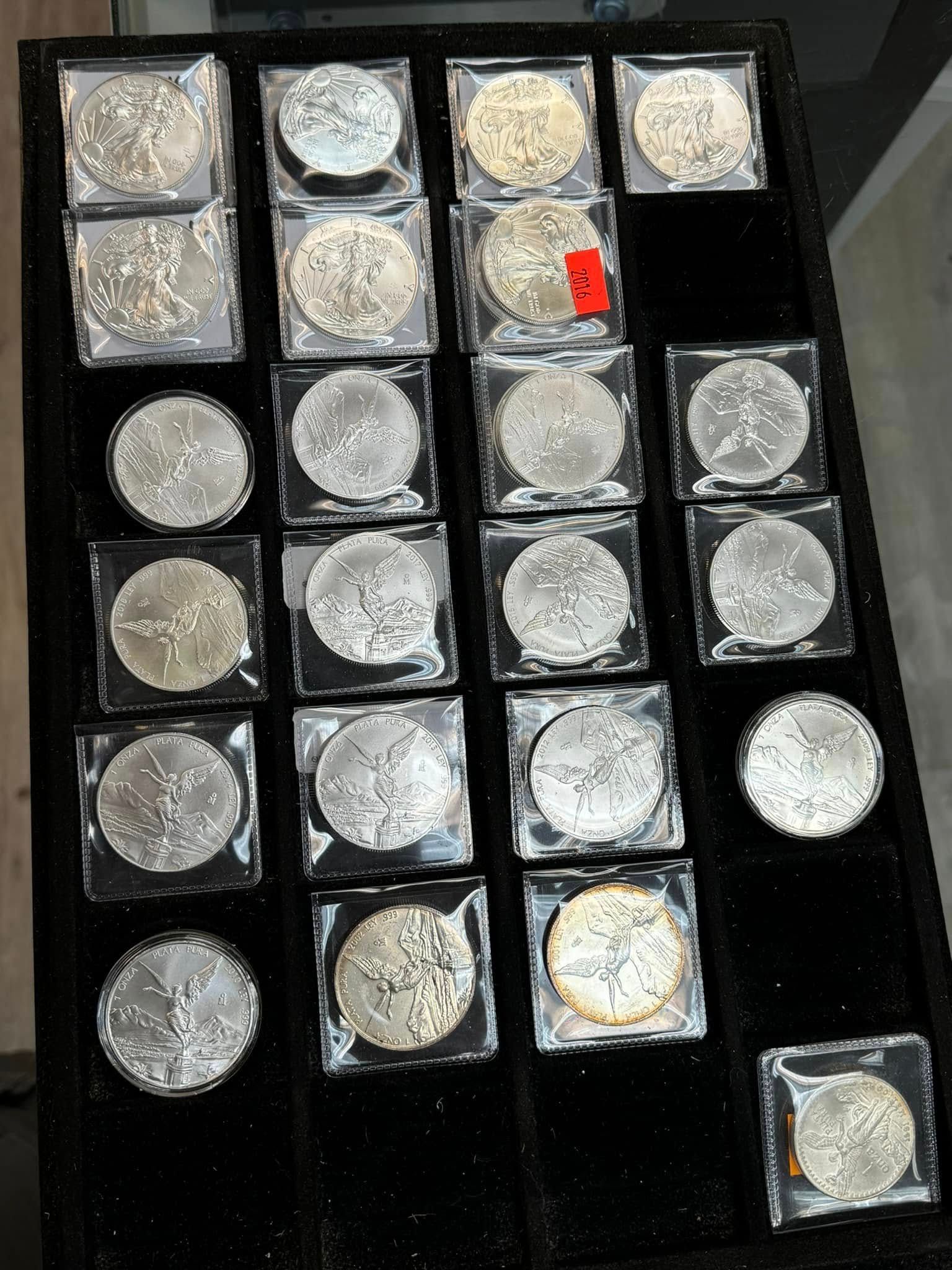 Tray of assorted coins in clear plastic sleeves, arranged in a grid on a black background.