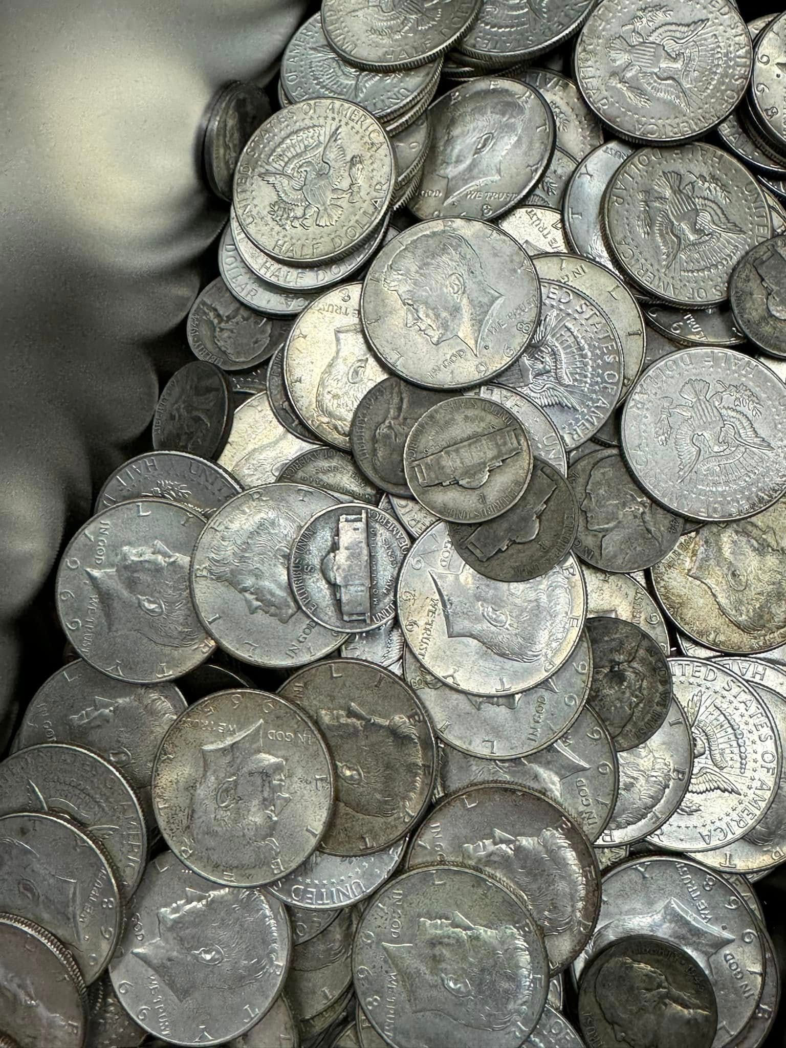 Pile of silver-colored coins stacked and scattered together, close-up view.