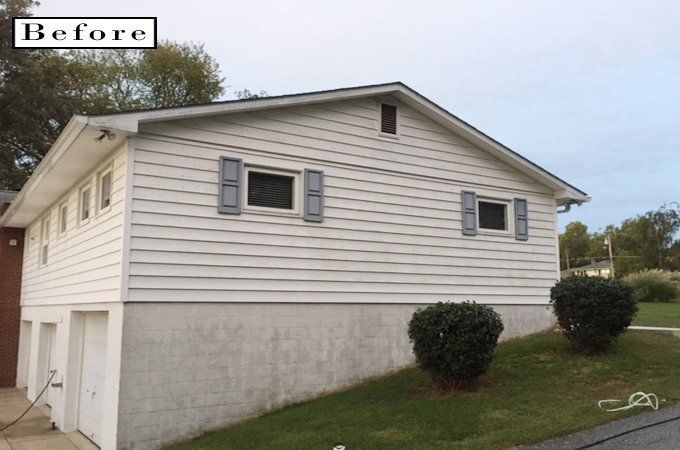 Before view of a beige split-level house with shrubs and a grassy yard