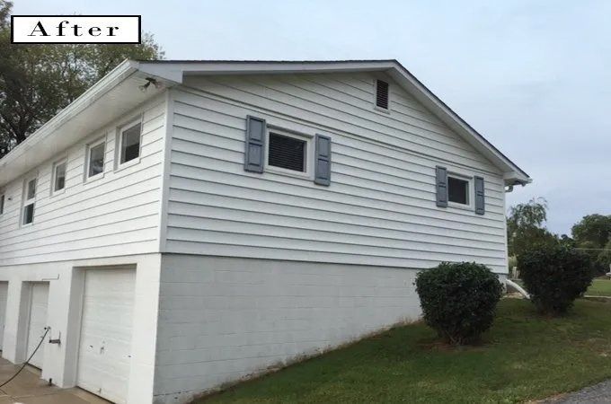 After photo of a white two-story house with garage doors and a small grassy yard