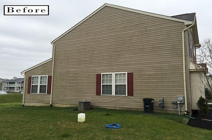 Before photo of a beige house exterior with red shutters and a lawn.