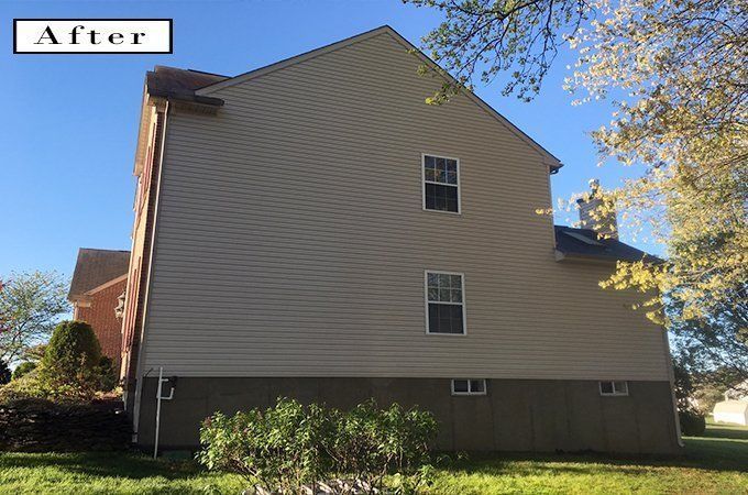 Rear view of a beige house with white trim and a small window, labeled “After” in the corner