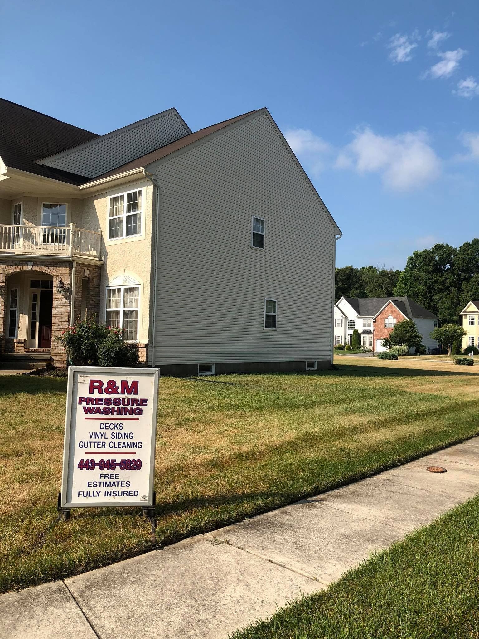 House exterior under repair with a company sign on the lawn and curved siding panel visible