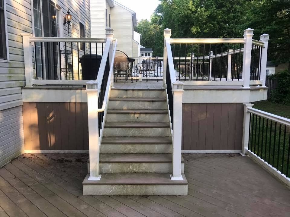 Backyard deck stairs with white railings leading to a raised porch