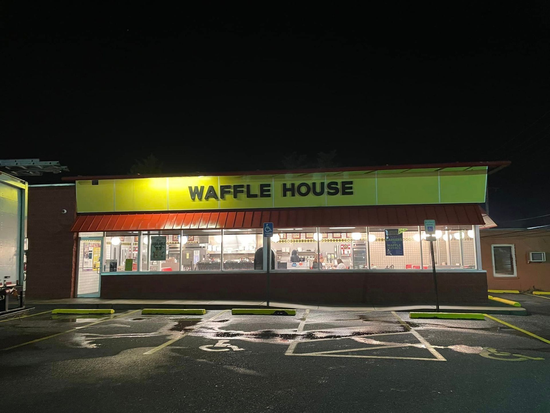 Waffle House restaurant at night with bright yellow sign and lit windows, empty parking lot in front