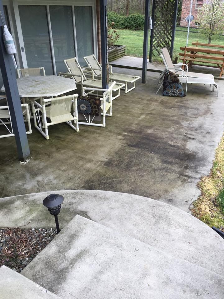 Concrete patio with outdoor table, chairs, grill, and a wooden bench by a sliding glass door.