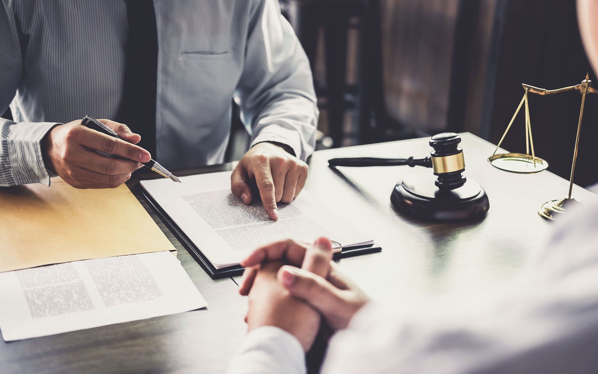 Two men are sitting at a table with a gavel and a scale of justice.