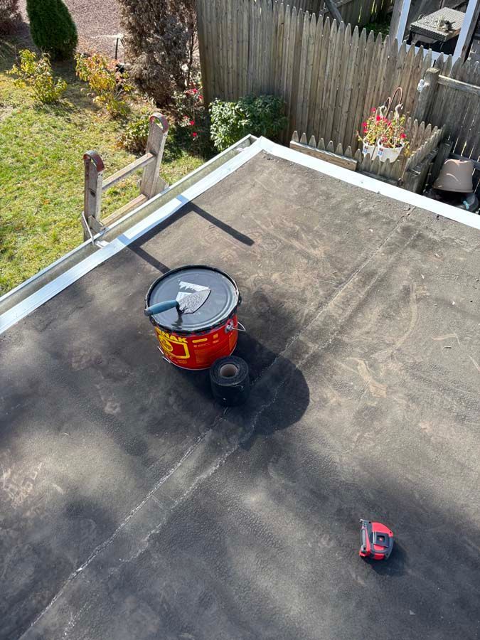 Flat rooftop with a bucket, tools, and a tape measure.