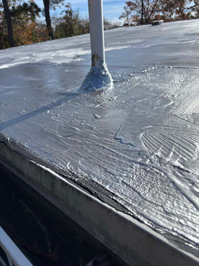 Close-up view of a roof with a metal edge and a pipe sealed with silver sealant.