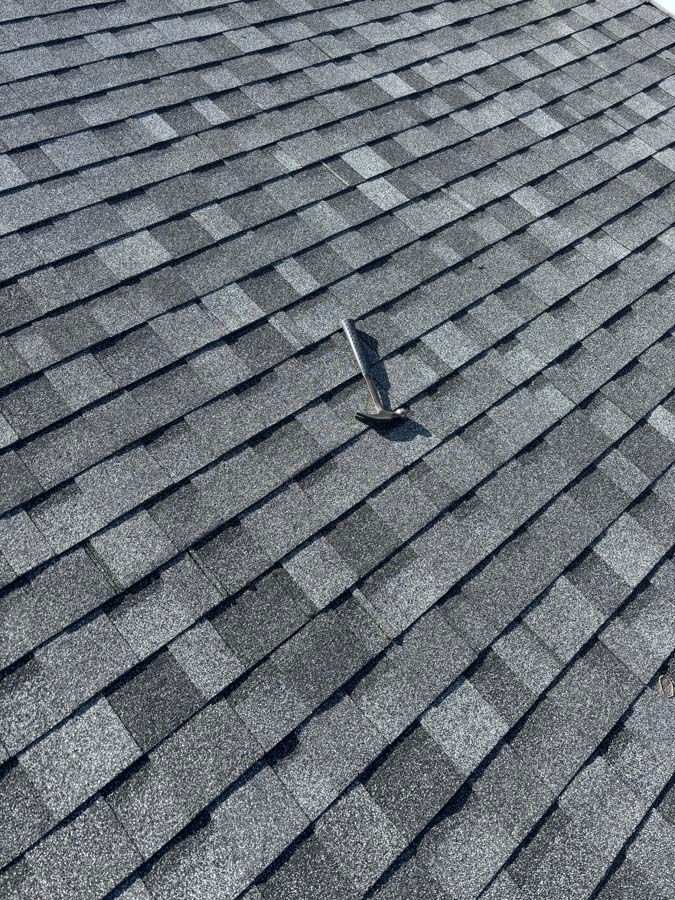 Gray asphalt shingle roof with a vent pipe protruding.