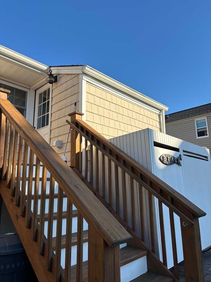 Wooden staircase leading up to a beige house with a white door, next to a white box.