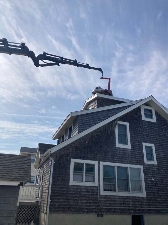 A two-story brown shingle house with a white porch and an SUV parked in front.