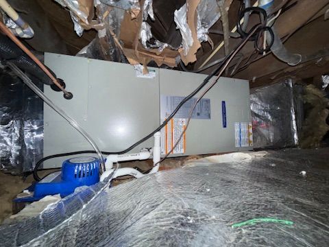 HVAC unit and ductwork in a cramped attic with exposed insulation and wiring