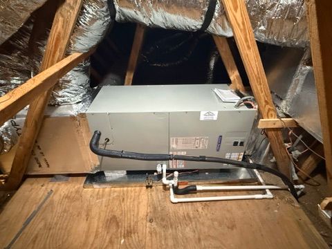 Attic HVAC unit with insulated ductwork and exposed wooden framing