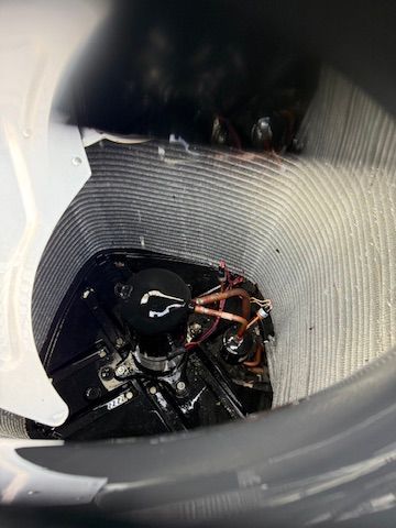 Inside a cylindrical tank, black mechanical parts and copper wiring are visible.