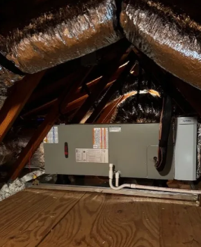 HVAC unit installed in an attic with insulated ductwork and a wooden floor platform
