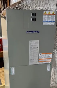 Gray electrical panel mounted on a wall, with warning labels and sticker labels.