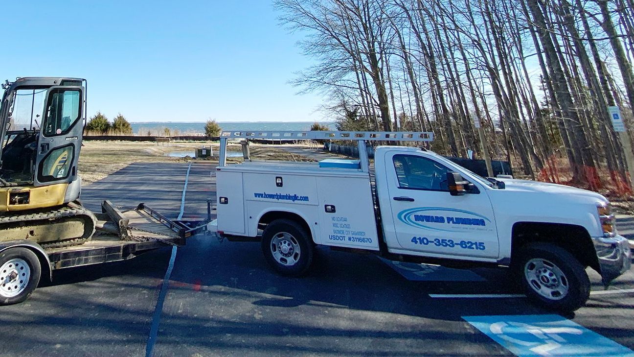 A white truck is towing a bulldozer on a trailer.